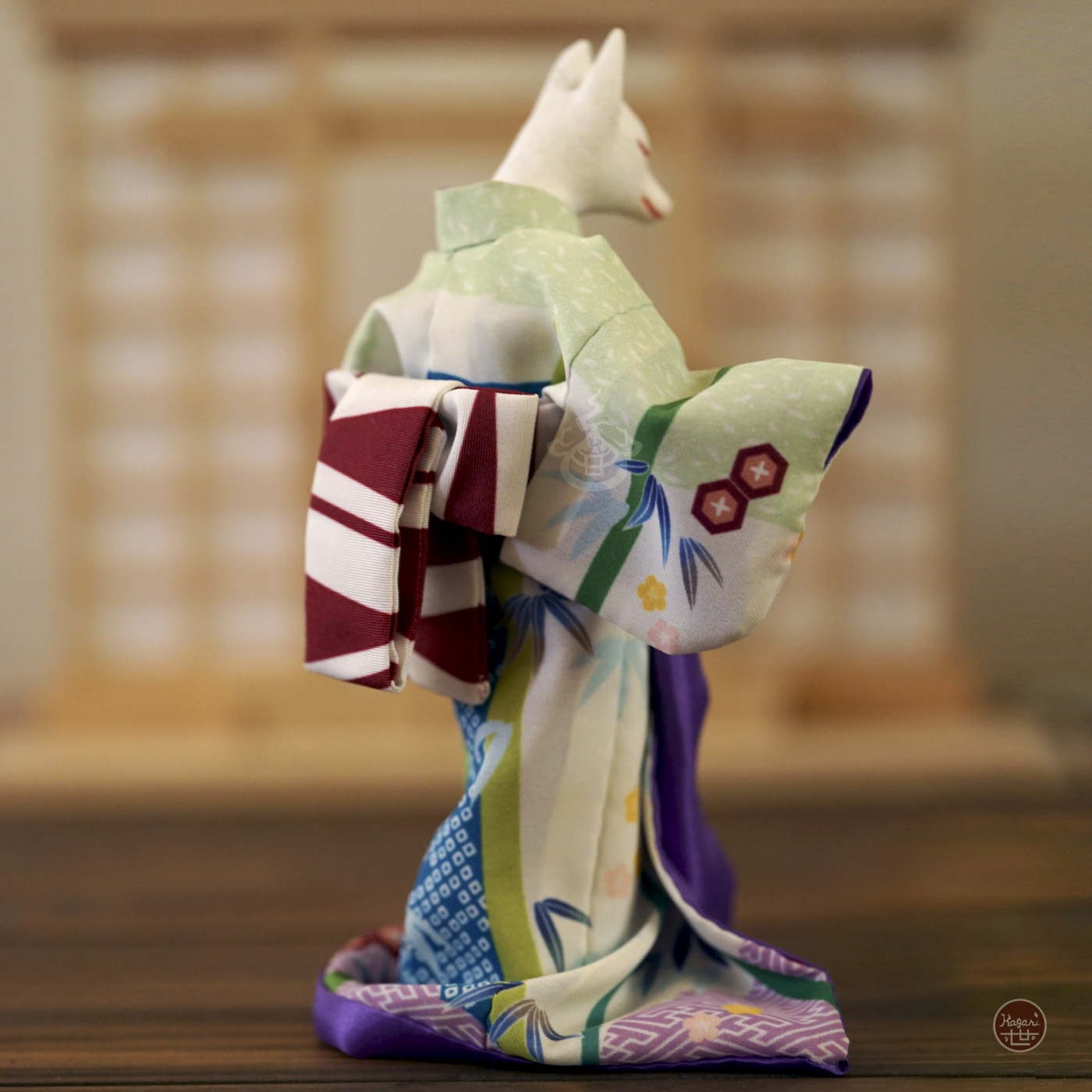 Rear angled view of a kimono-wearing fox figure in pale green and blue fabric with traditional patterns