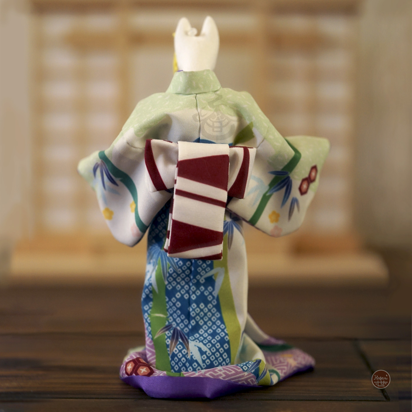 Back view of a kimono-wearing fox figure with a red and white obi tied in a ribbon-like tsunodashi style