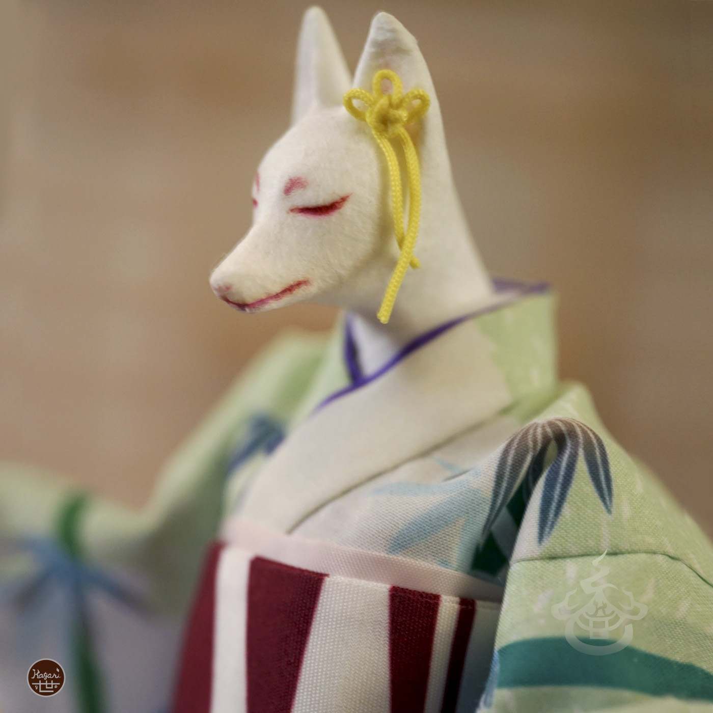 Close-up of a fox figure with a vermilion mouth, closed eyes, and yellow flower-knot earrings
