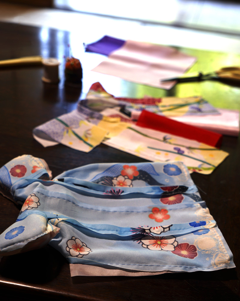 Small kimono in progress with blue fabric and plum blossom patterns, photographed during the handcrafting process