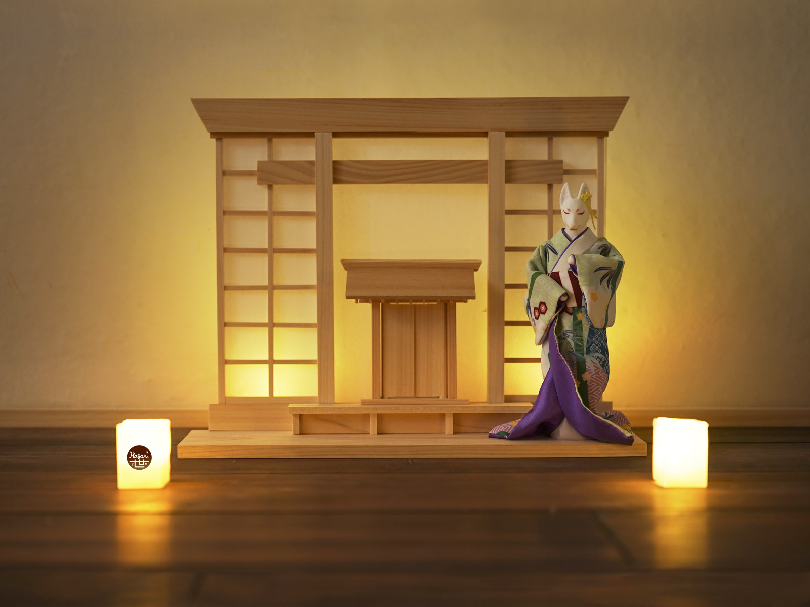 Kimono-wearing fox figure standing before a shrine-inspired wooden display, with small washi paper lamps in the foreground